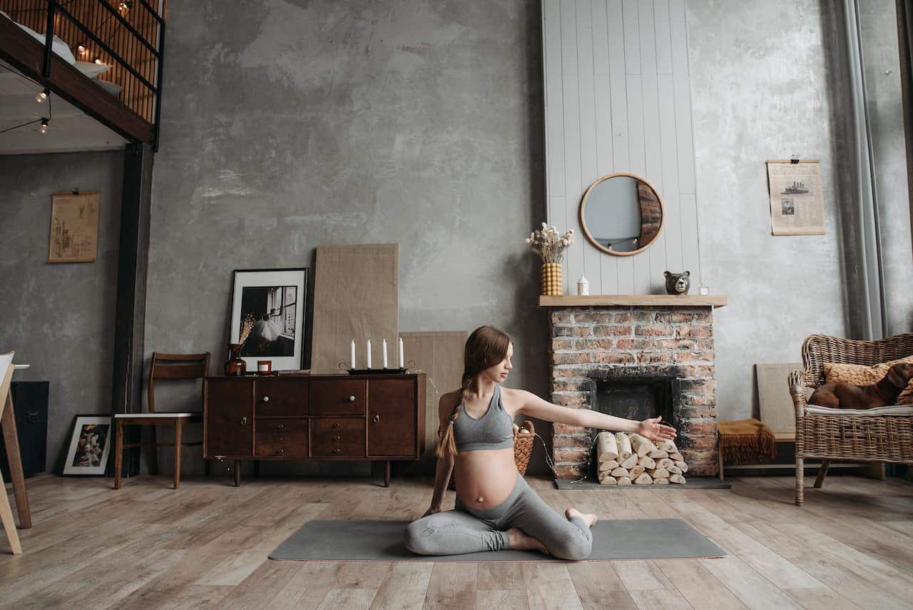 Pregnant woman exercising by doing yoga at home.